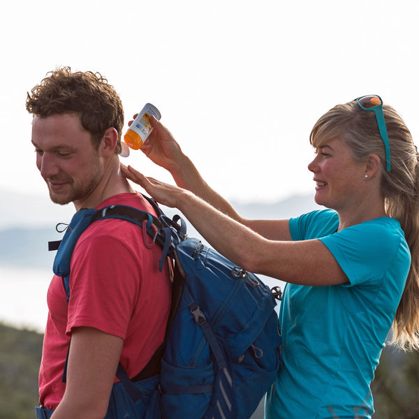 Lifestyle image of a woman applying Care Plus Sun Cream on to a mans neck when outdoors in the sun
