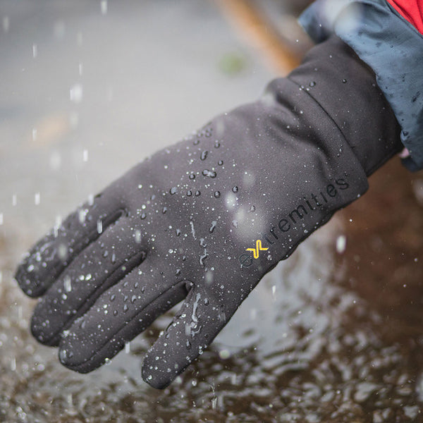 A lifestyle photograph of an Extremities Waterproof Power Liner Glove worn in the rain with water beading of it