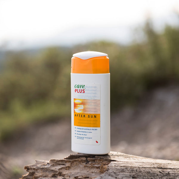 Lifestyle image of Care Plus after sun lotion 100ml bottle photographed outside placed on a log