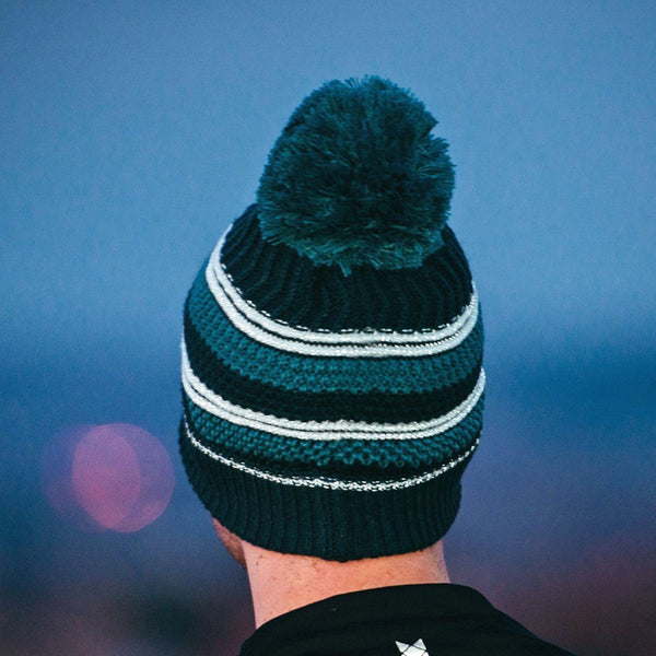 Lifestyle image of a person wearing an Extremities Capella reflective thermal winter bobble hat in twilight 