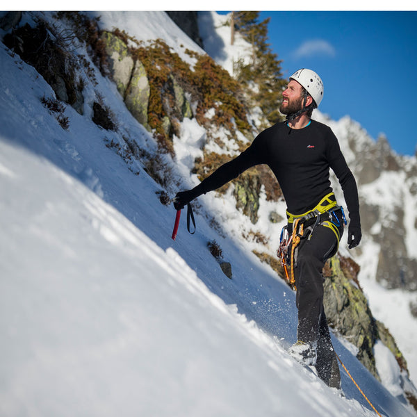 Lifestyle photograph of a man climbing on the snow covered Alps in winter whilst wearing a Sub Zero merino wool long sleeve thermal mid layer top and leggings